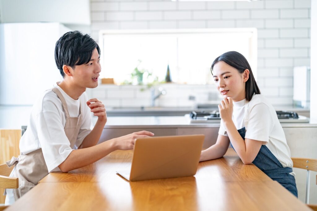 ダイニングでPCを見ながら話をしている夫婦