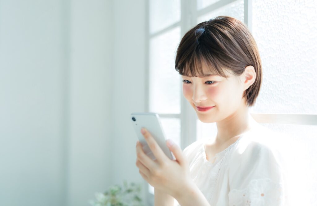 窓際でスマホを見ている女性