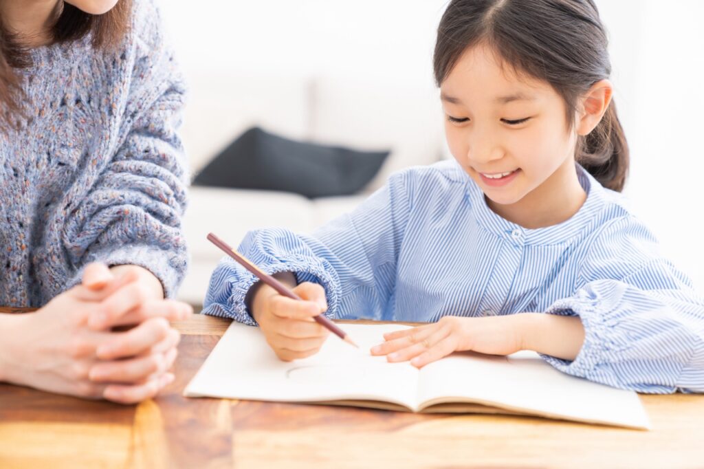 お母さんに見守られながら勉強する女の子